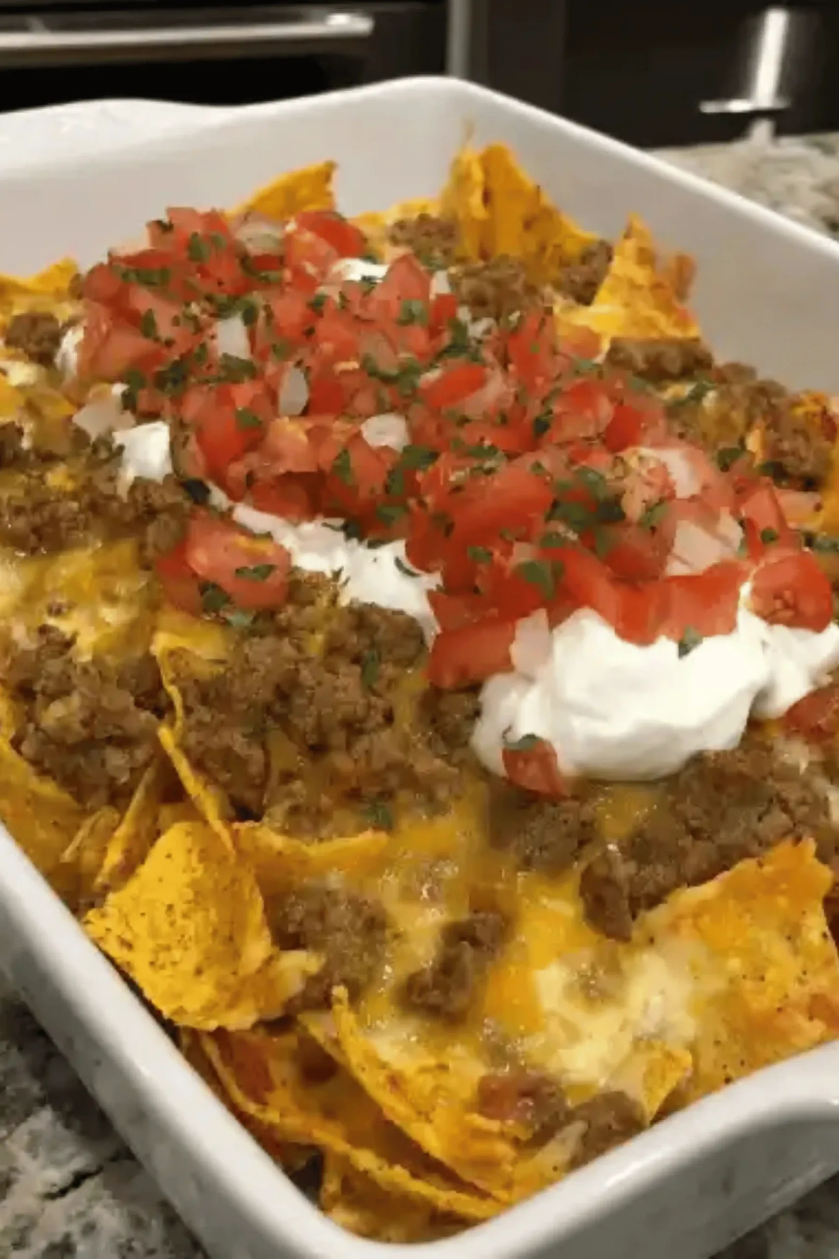 Cheesy Dorito Taco Casserole layered with seasoned beef, melted cheese, and crushed Doritos topped with sour cream and Pico de Gallo.