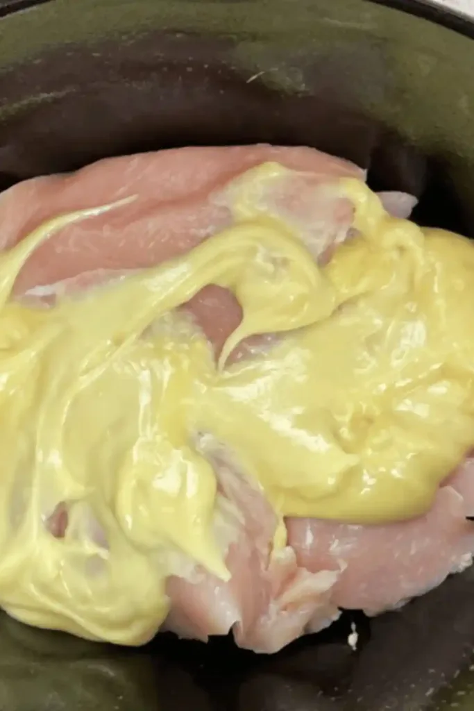 Chicken breasts arranged in slow cooker before adding soup