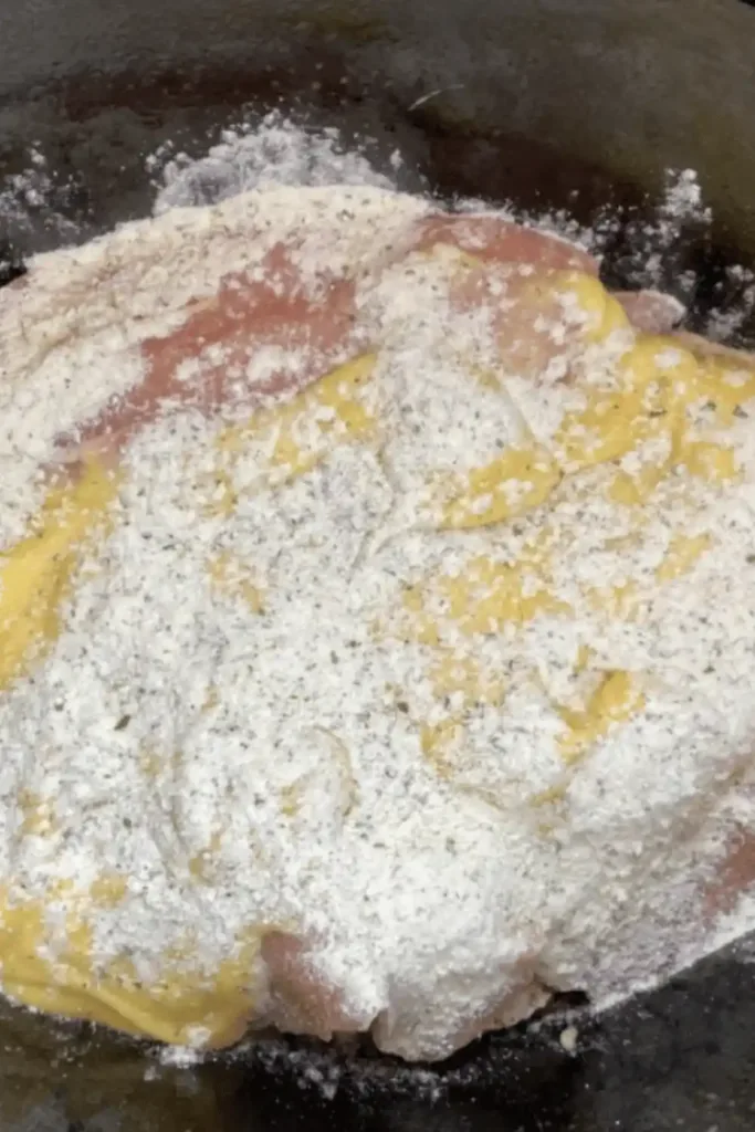 Pouring cream of chicken soup and ranch seasoning over chicken in slow cooker