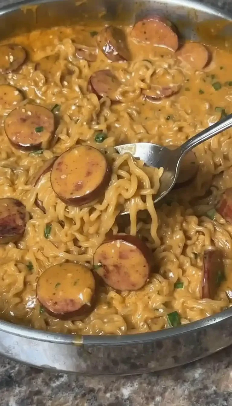 Creamy spicy garlic noodles topped with sausage in a bowl