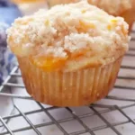 Freshly baked peach cobbler muffins topped with a crumbly streusel.