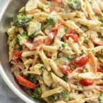 Colorful bowl of spring pasta with fresh vegetables and herbs